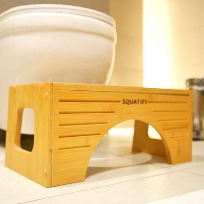 Wooden squatting stool with 'Squatify' branding in a bathroom setting.